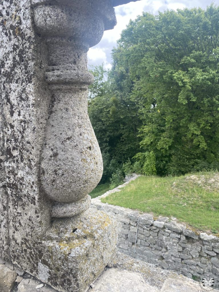 Zbliżenie na narożnik kamiennej balustrady tarasu – stojąca tralka, w tle mur