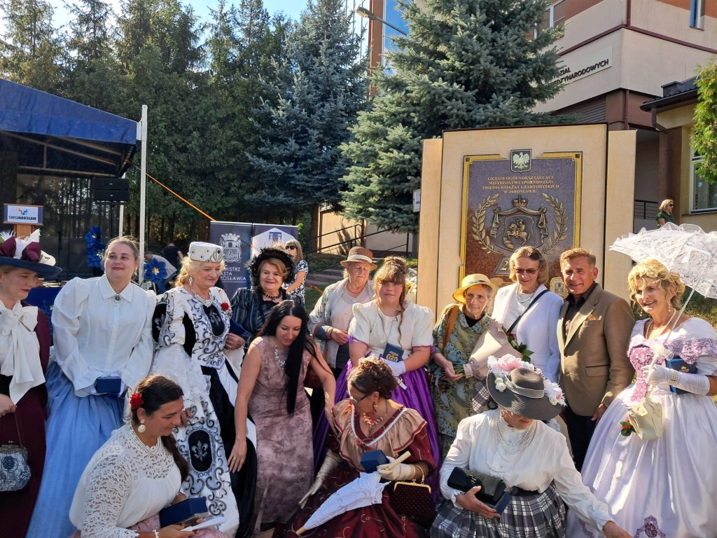 Grupa osób na tle tablicy pamiątkowej